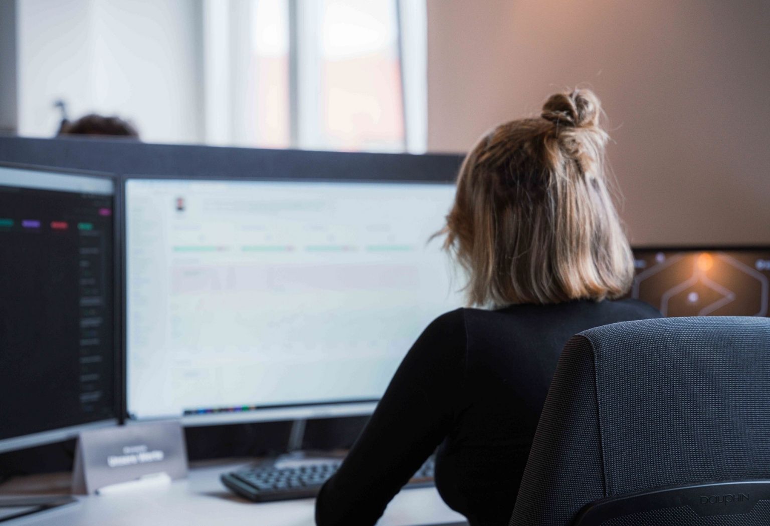 Eine Frau an einem Schreibtisch mit zwei Monitoren, die an einem Projekt in einer Internetagentur arbeitet.